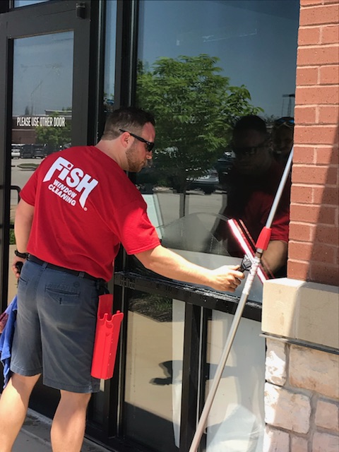 Image of Window Cleaner Cleaning Storefront Window with a Mop